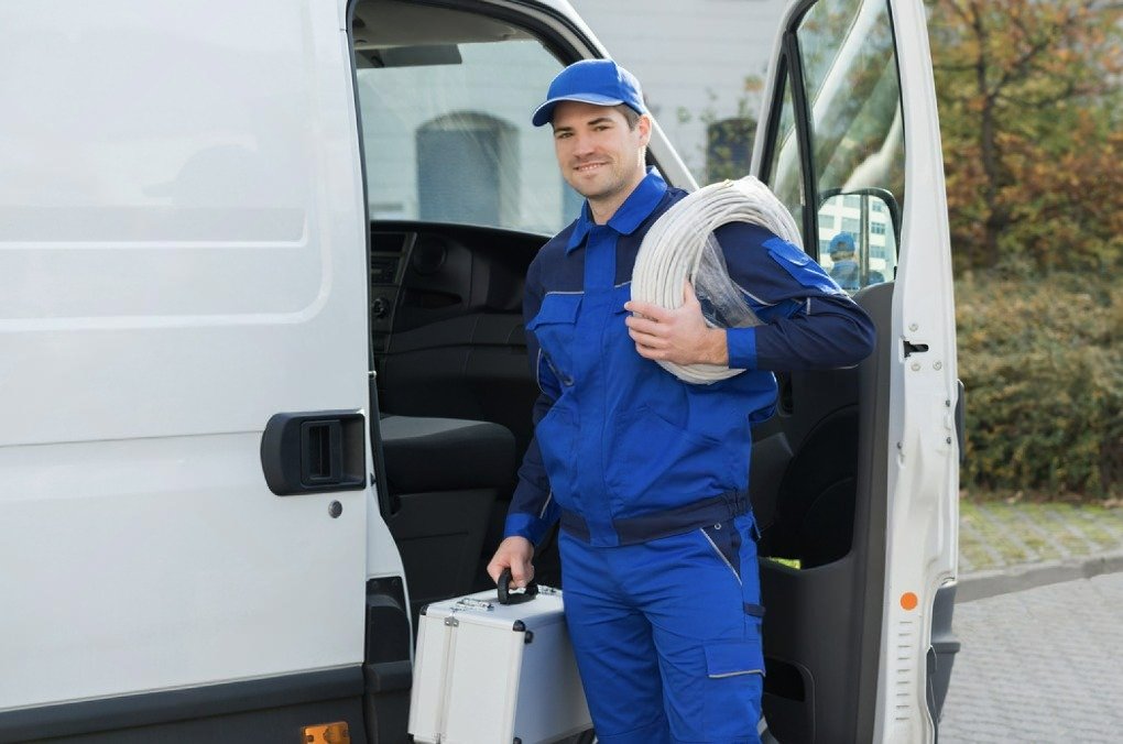Plombier en tenue bleue arrivant sur place avec son matériel